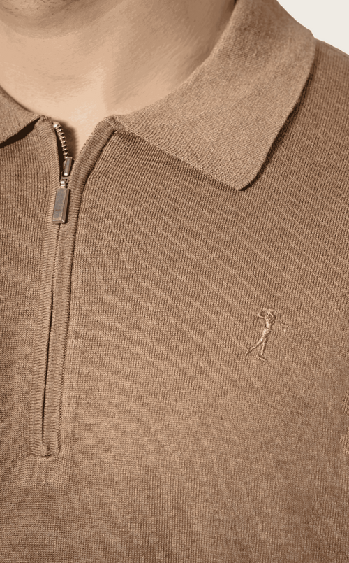 Close-up of a  silk polo shirt with a small logo on a neutral background